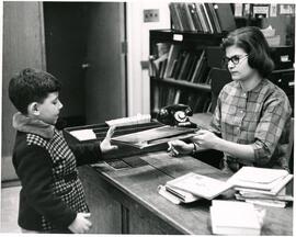 Young boy checking out book, Jewish Public Library.