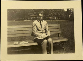 Maurice Zbriger seated on park bench, writing