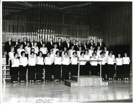 Workmen's Circle choir concert, interior group portrait of men and women standing on stage in front of an organ.