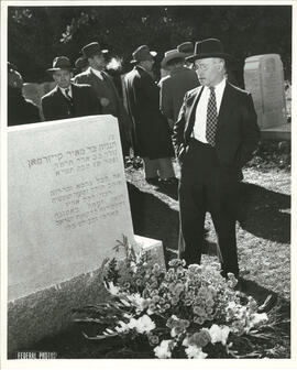 J.I. Segal standing beside gravestone of Reuben Brainin, Montreal.