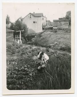 Exterior snapshot, woman and child working in garden behind of the Perlmutter's Economy Store, An...
